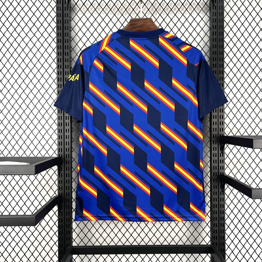 Back of the blue Spain short sleeve shirt on a hanger, with diagonal red and yellow stripes, navy geometric panels and solid navy sleeves