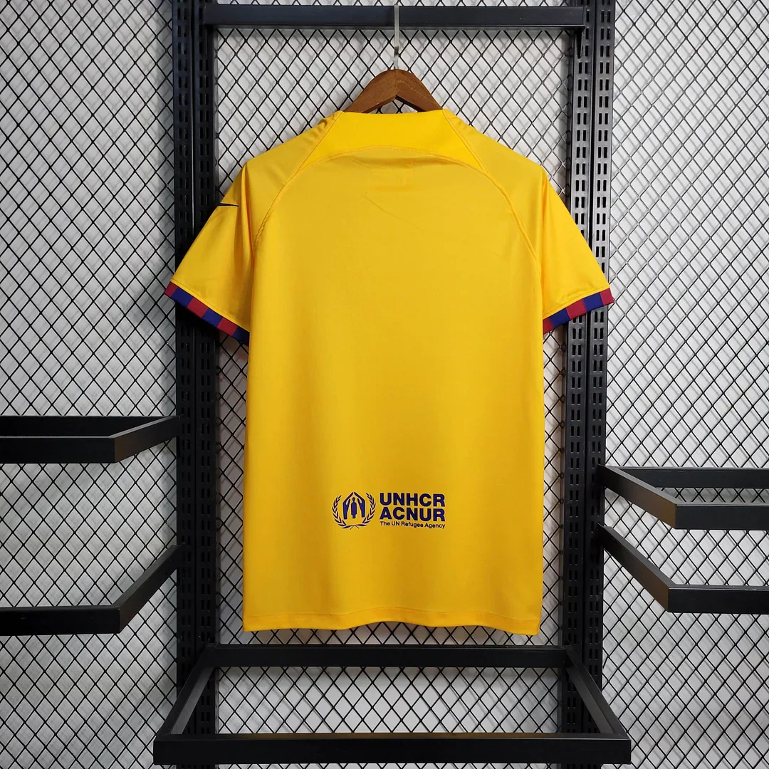 Back view of the yellow Barcelona football shirt with red and blue sleeve trim, shown on a hanger.