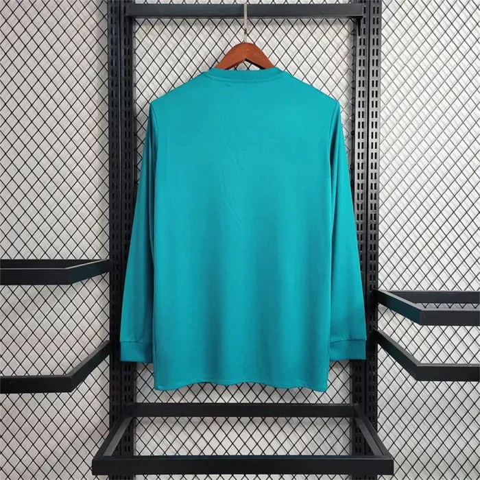 Real Madrid teal long sleeve football shirt, back view with a plain teal body and matching collar and cuffs
