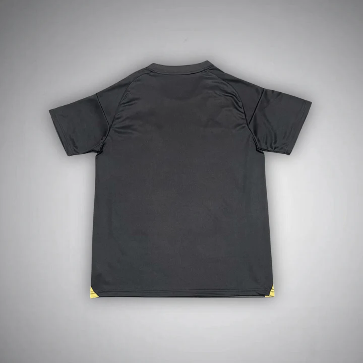 Real Madrid black short sleeve football shirt, plain back view with a round collar and small gold panels at the lower side edges