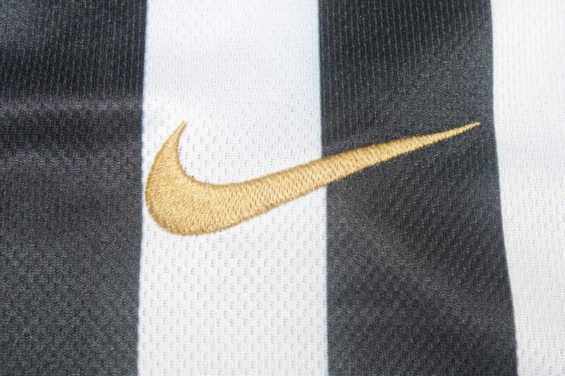 Close-up of the gold stitched swoosh across black and white vertical stripes on the Santos FC shirt