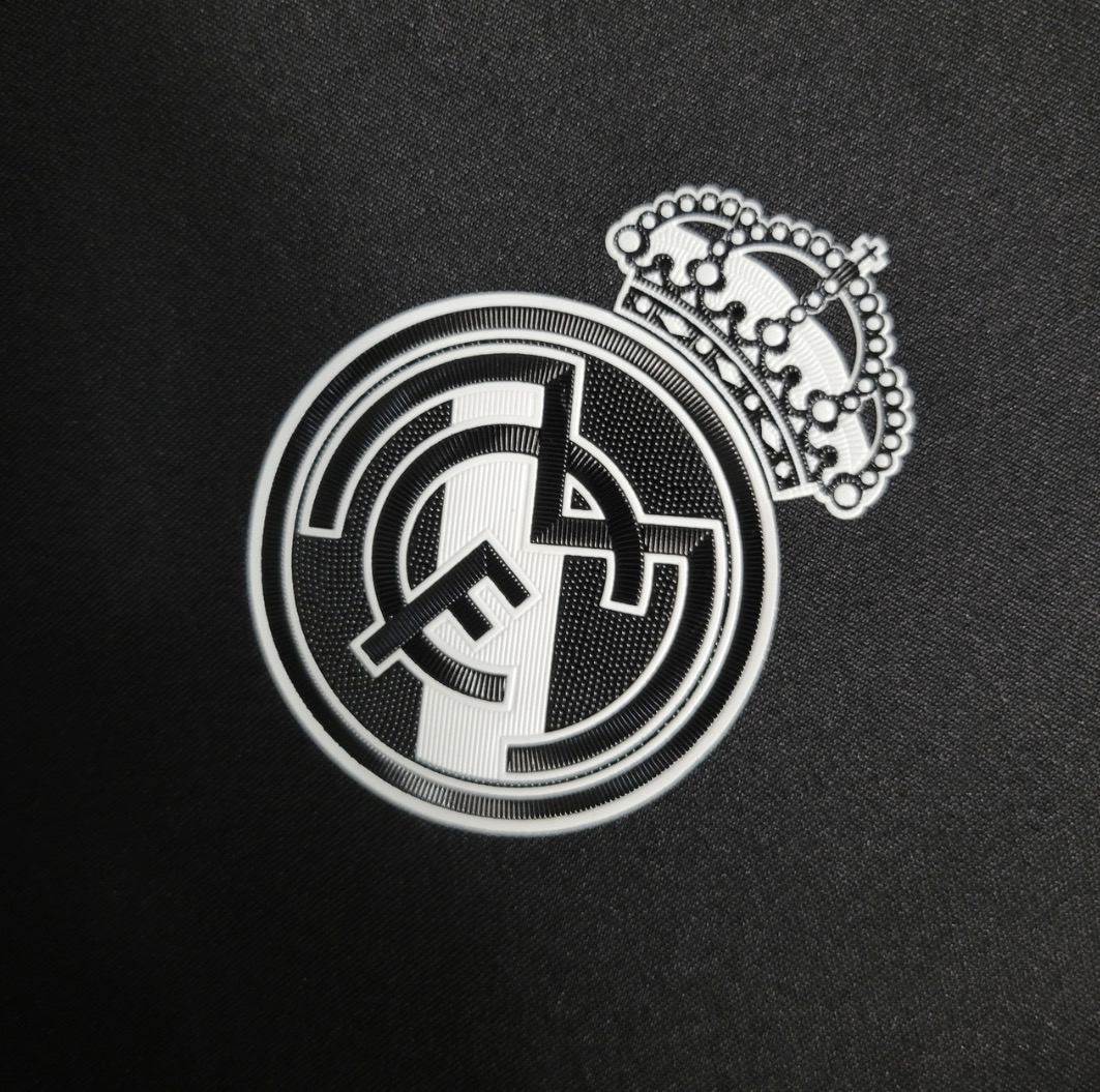 White Real Madrid crowned crest close-up against the dark football shirt