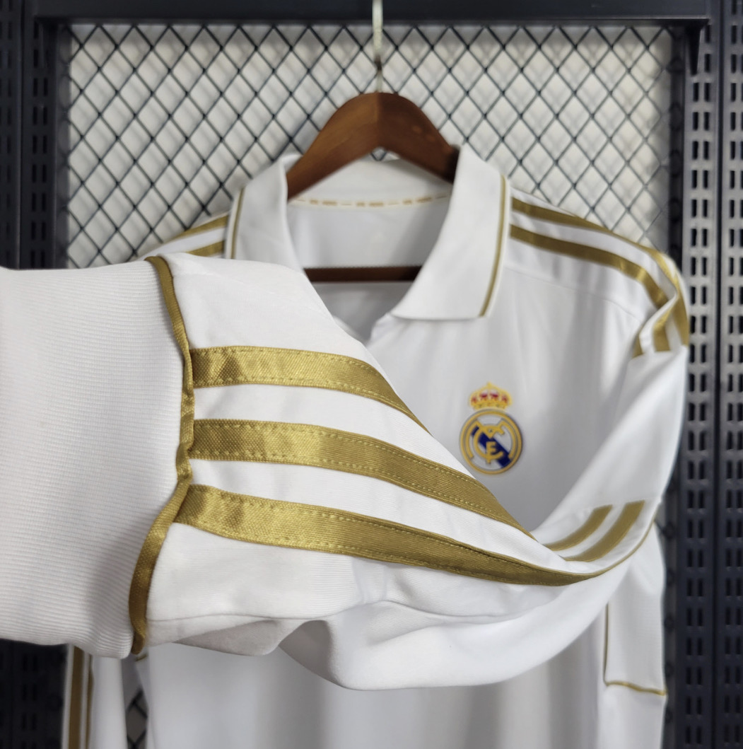 Real Madrid white long sleeve football shirt sleeve close-up with three gold stripes, a white ribbed cuff and gold edging, with the collar and crest behind